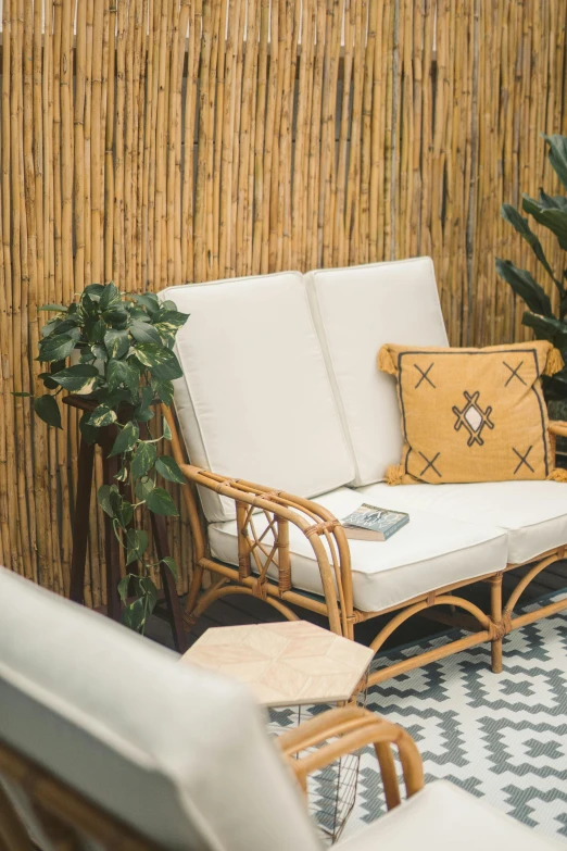 a white couch sitting on top of a tiled floor, a portrait, inspired by Riad Beyrouti, unsplash, made of bamboo, plants and patio, brown, two