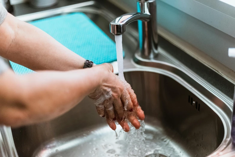 a person washing their hands in a sink, by Daniel Lieske, pexels, fan favorite, stainless steel, nursing, realistic water