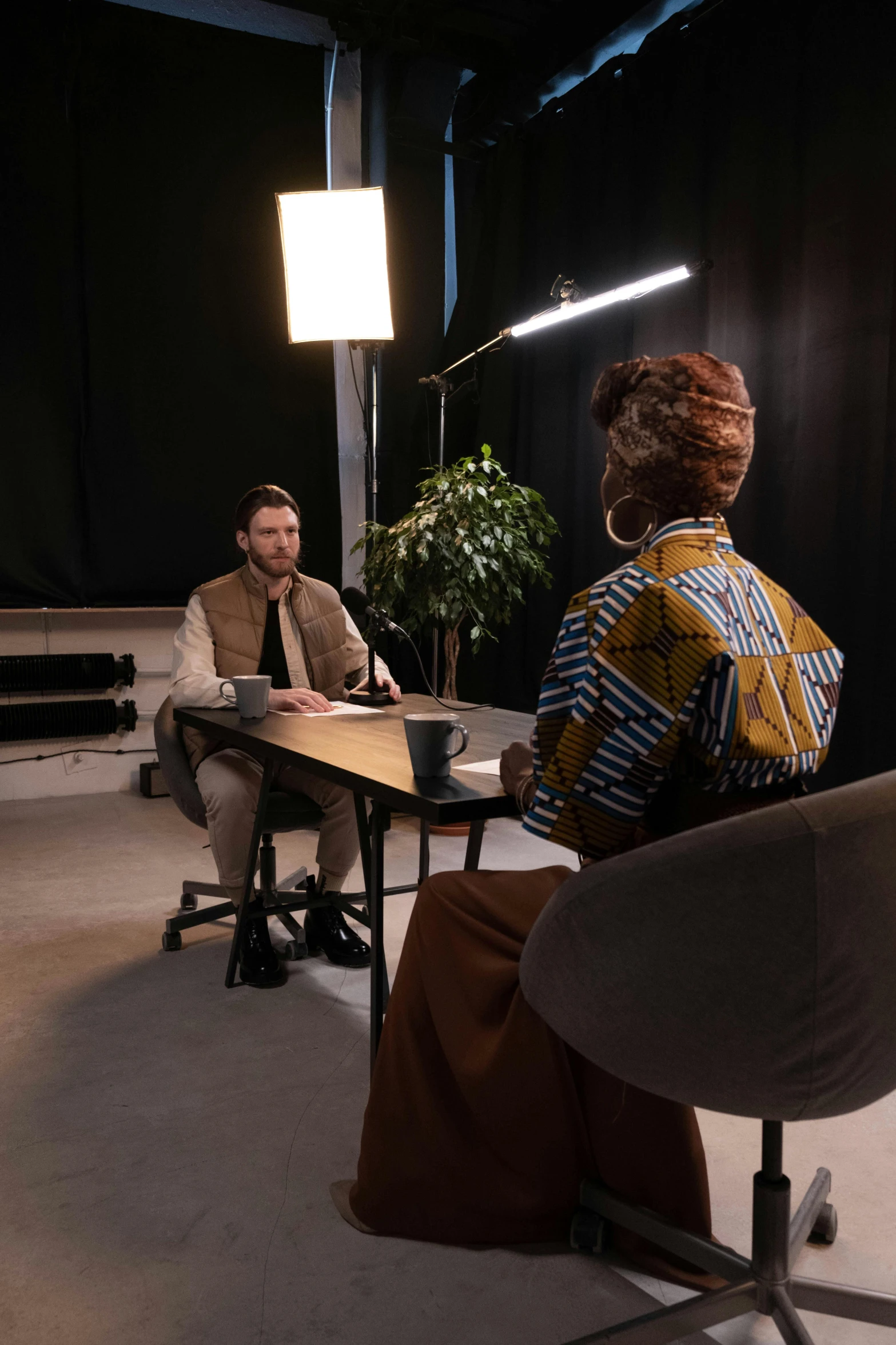 a group of people sitting around a table in a room, virtual set, two still figures facing camera, augusta savage, shot with sony alpha