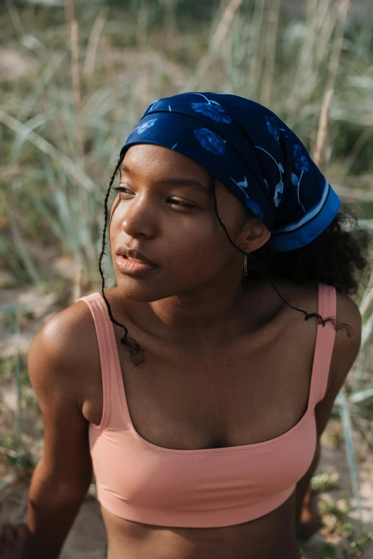 a woman in a pink top holding a frisbee, by Lily Delissa Joseph, trending on unsplash, renaissance, brown skin like soil, dark blue beanie, bandana, movie still of a tired