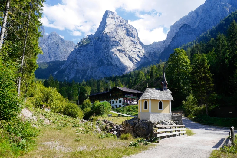 a small church with a steeple in the background, an album cover, inspired by Franz von Lenbach, pexels contest winner, solo hiking in mountains trees, chalet, vacation photo, youtube thumbnail