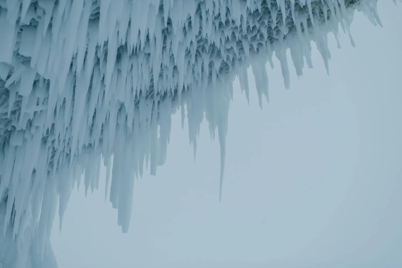 a group of people standing on top of a snow covered slope, an album cover, by Andrew Geddes, pexels contest winner, romanticism, high detailed thin stalagtites, icicle, blue gray, 3/4 view from below