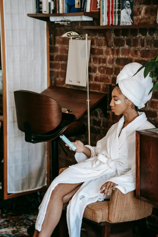 a woman sitting in a chair with a towel on her head, trending on pexels, renaissance, wearing white robe, afro tech, manicured, her hair pinned up