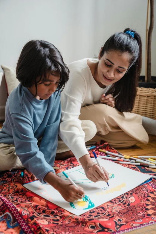 a woman and a child are drawing on the floor, pexels contest winner, a portrait of rahul kohli, coloring book style, promotional image, fashion