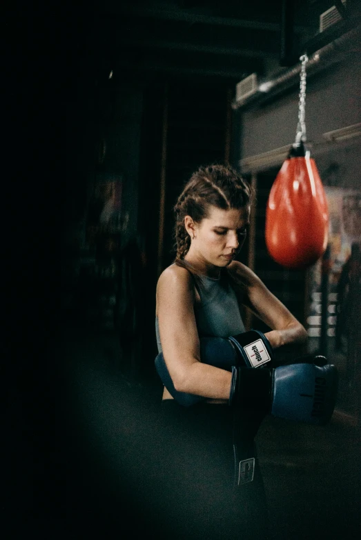 a woman standing next to a punching bag, by Sara Saftleven, pexels contest winner, happening, hunched shoulders, sitting, profile image, sports photo