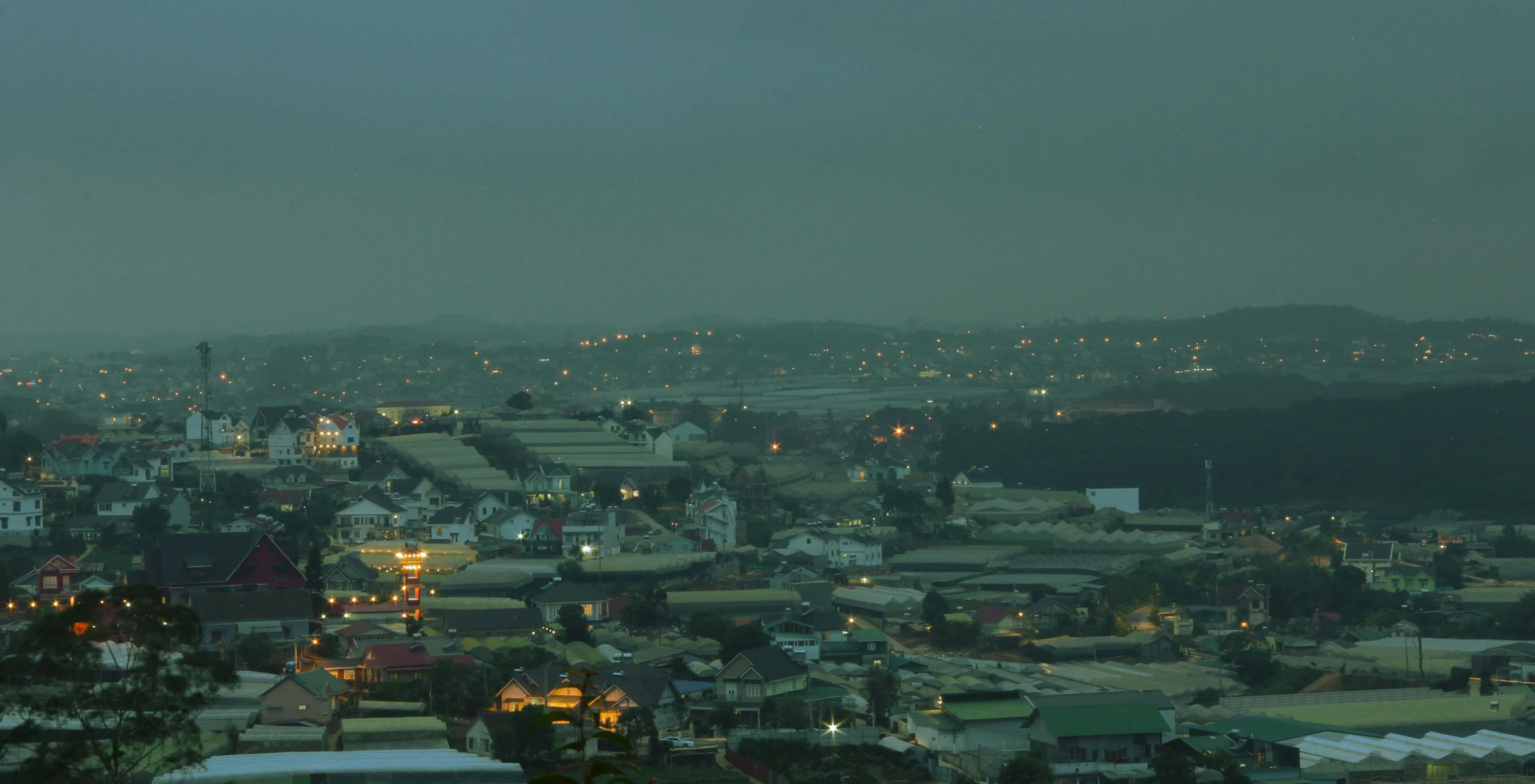 a view of a city at night from the top of a hill, mingei, industrial setting, grey, green, night time photograph