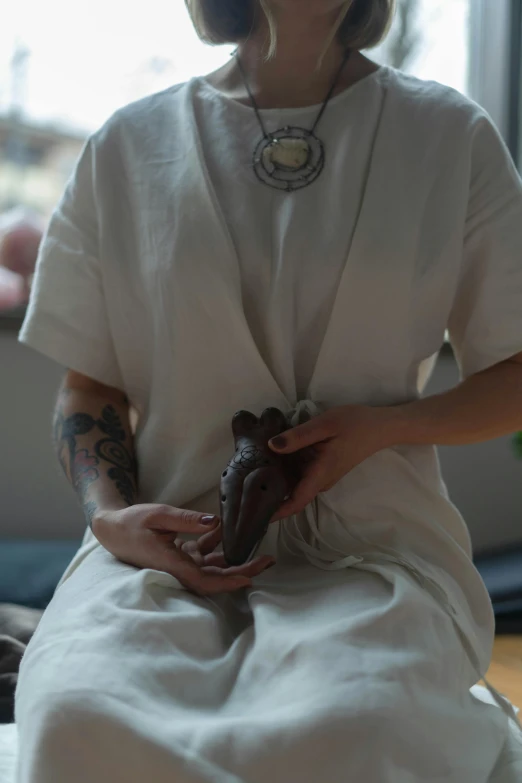 a woman sitting in front of a window holding a donut, a tattoo, by Jessie Algie, unsplash, process art, anatomically correct heart, dragon-inspired cloth robes, detailed clay model, health spa and meditation center