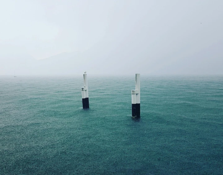 two poles sticking out of the ocean on a foggy day, pexels contest winner, turbines, aerial footage, ventilation shafts, cyan mist