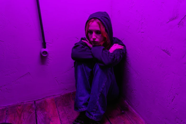 a woman sitting on the floor in a purple room, inspired by Nan Goldin, pexels, antipodeans, girl wearing hoodie, teenage boy, stood in a tunnel, concerned