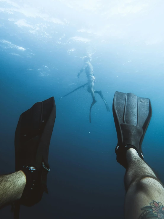 a couple of people that are swimming in the water, bottom of ocean, long flowing fins, detailed shot legs-up, holding trident