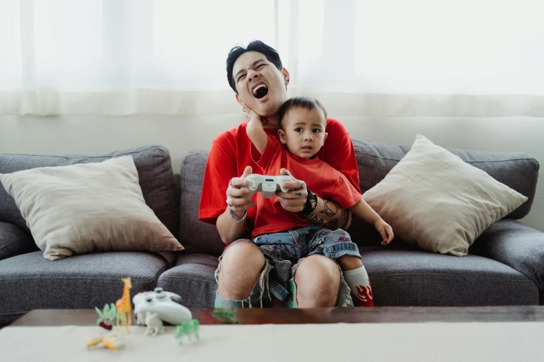 a man sitting on top of a couch holding a child, pexels contest winner, gaming, avatar image, asian man, rocking out