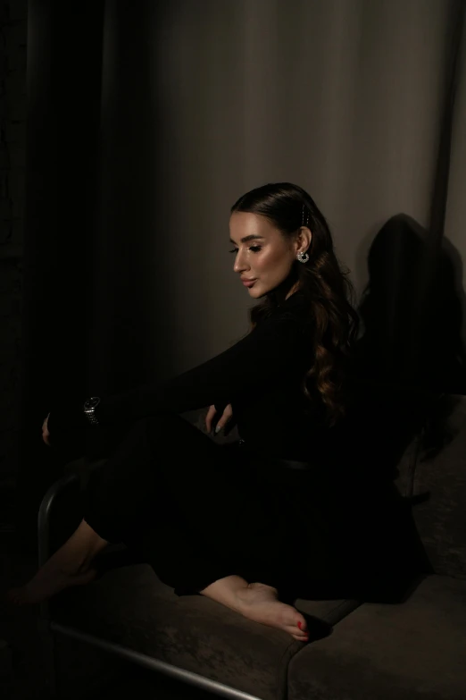 a woman sitting on a couch in a dark room, by Emma Andijewska, hurufiyya, olivia culpo, profile image