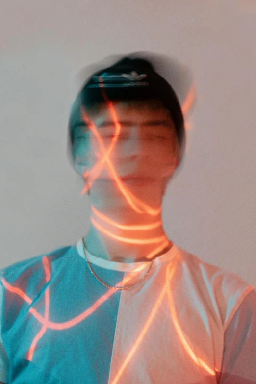 a man standing in front of a white wall, an album cover, inspired by Yanjun Cheng, trending on pexels, holography, glowing face, declan mckenna, orange neon backlighting, light traces