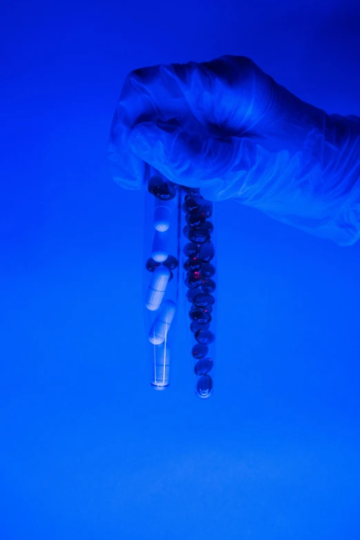 a close up of a person's hand holding a toothbrush, a microscopic photo, by Ryan Pancoast, conceptual art, dark blue spheres fly around, pathology sample test tubes, high quality photo, beads