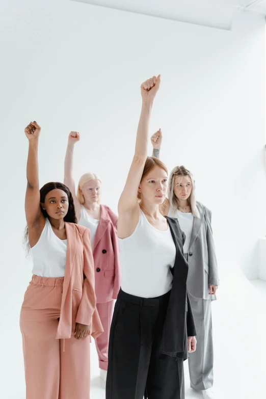 a group of women standing in a line with their arms in the air, trending on pexels, feminist art, raised fist, human actress, product shot, concerned