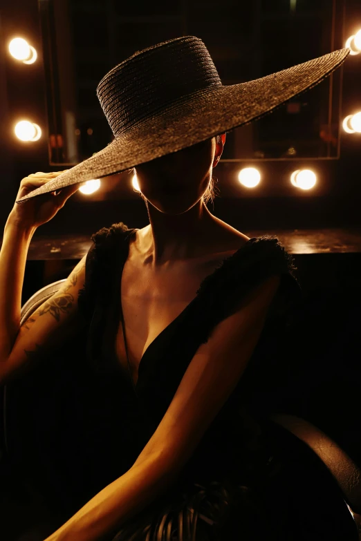 a woman sitting in a chair with a hat on, pexels contest winner, renaissance, reflecting light in a nightclub, low cut dress, theater dressing room, lit from behind