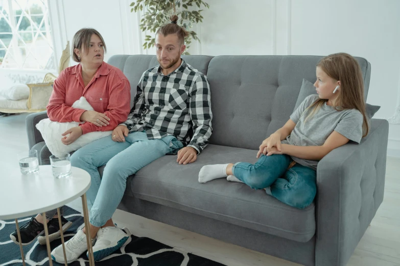 three people sitting on a couch in a living room, by Adam Marczyński, pexels, husband wife and son, low quality footage, studio photo, struggling