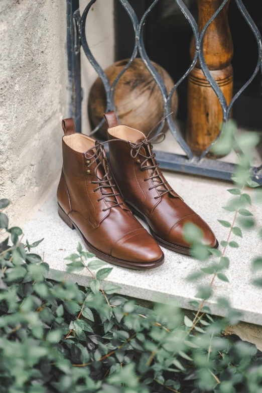 a pair of brown shoes sitting on top of a window sill, a portrait, inspired by Salomon van Abbé, unsplash, wearing leather, botanicals, made of glazed, highest quality