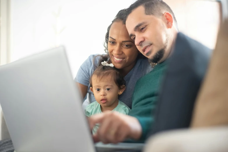 a man and woman sitting on a couch looking at a laptop, husband wife and son, square, hispanic, thumbnail