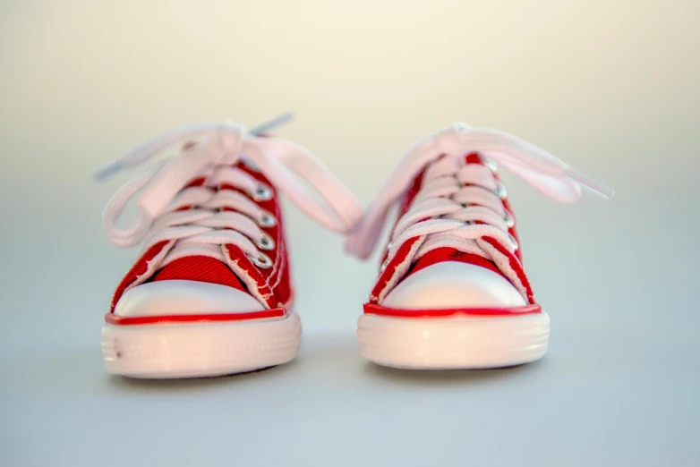 a pair of red sneakers with white laces, a photo, pexels, hyperrealism, cuteness, forward facing, incredibly cute, mixed art