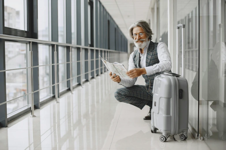 a man sitting on a suitcase reading a newspaper, pexels contest winner, silver hair and beard, airport, avatar image, elegantly dressed