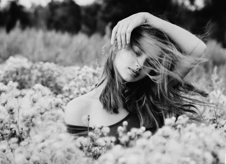 a black and white photo of a woman in a field of flowers, a black and white photo, by Ksenia Milicevic, pexels, art photography, soft hair, hair floating covering chest, cute young woman, medium format