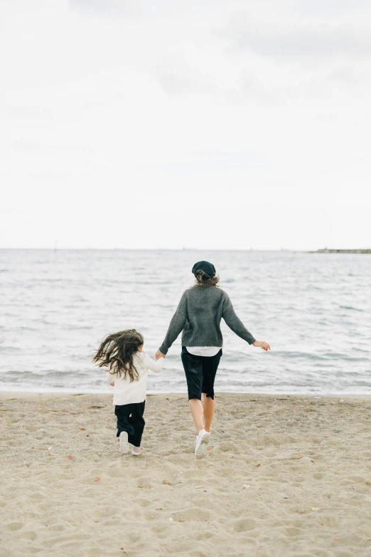 a woman and a child running on a beach, pexels contest winner, facing away, slightly pixelated, profile image, young girls