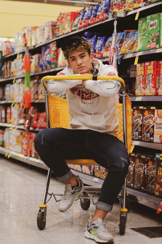 a man sitting in a shopping cart in a grocery store, an album cover, inspired by John Luke, trending on pexels, diego fernandez, stylish pose, cereal, beautiful gorgeous