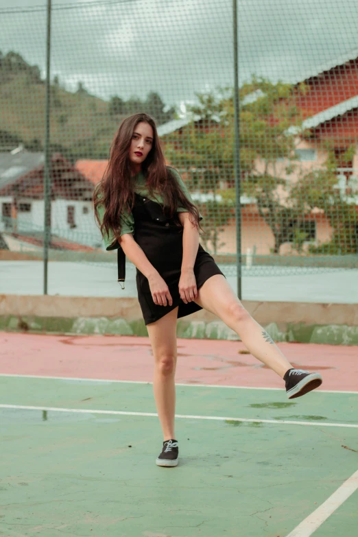 a woman standing on top of a tennis court holding a racquet, by Julia Pishtar, pexels contest winner, realism, wearing a punk outfit, she wears a dark green dress, gif, teenager girl