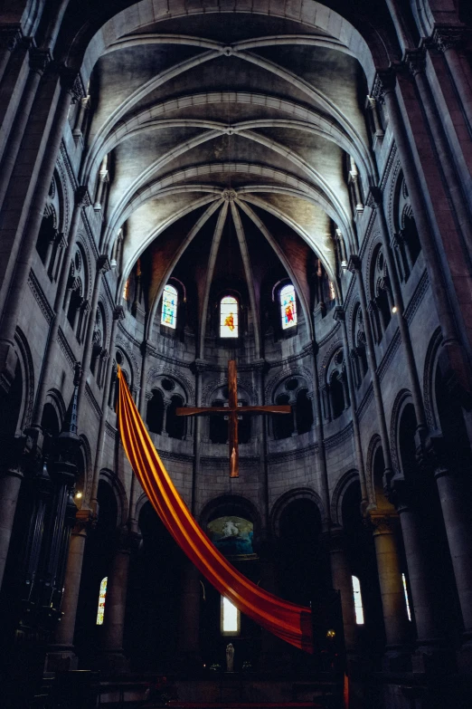the interior of a cathedral with a red cloth hanging from the ceiling, pexels contest winner, romanesque, dark grey and orange colours, montreal, high-angle, color”
