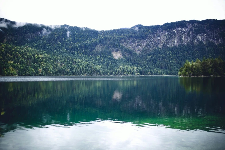 a body of water with a mountain in the background, green water, instagram picture, forest with lake, focused photo