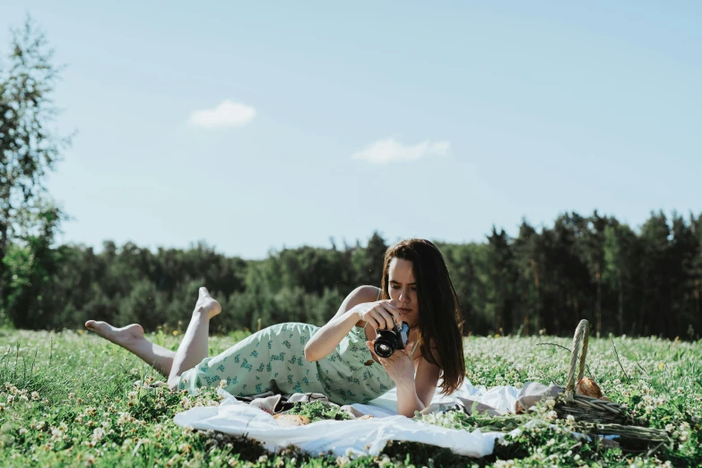 a woman laying in the grass with a bottle of wine, by Emma Andijewska, happening, picnic, full body image, medium format, candid photography