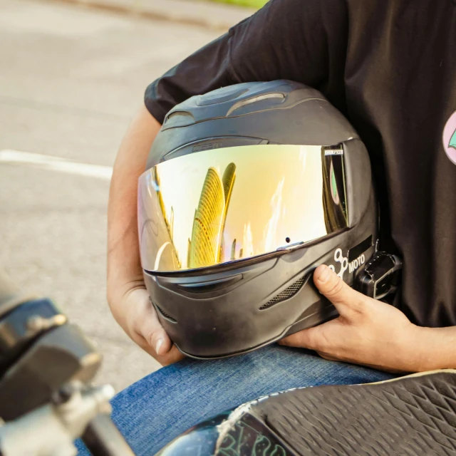 a person sitting on a motorcycle with a helmet on, iridescent visor, brown, rectangle, black