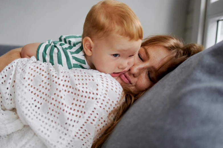 a woman holding a baby on top of a couch, pexels contest winner, happening, soft lulling tongue, covered with blanket, cute boy, close up shot from the side