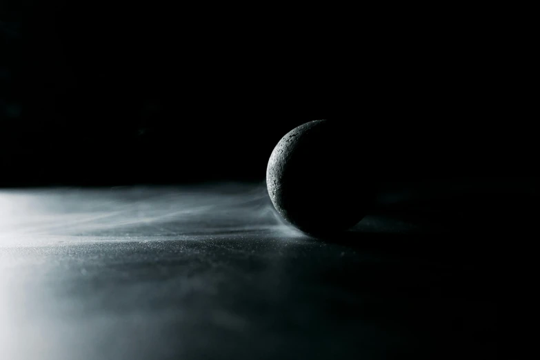 a black and white photo of a tennis ball, inspired by Michal Karcz, unsplash contest winner, space art, volumetric fog, moon surface, in a pitch black room, blurred space