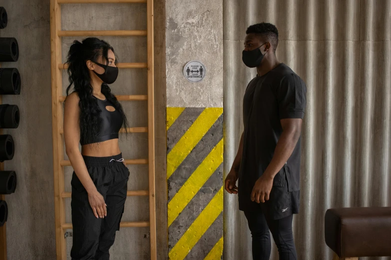 a man and a woman standing next to each other, by Nina Hamnett, pexels contest winner, afrofuturism, wearing fitness gear, black facemask, construction, photoshoot for skincare brand