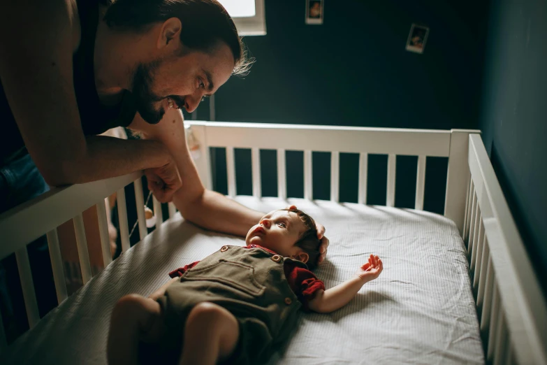 a man standing over a baby in a crib, pexels contest winner, laying back on the bed, avatar image, up close picture, child