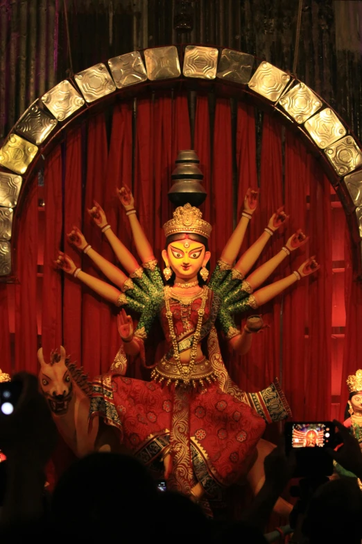 a group of people taking pictures of a statue, pexels contest winner, bengal school of art, dark goddess with six arms, 3 spring deities, in a temple, slide show