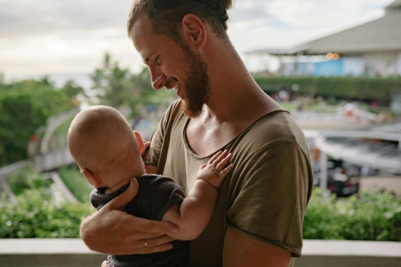 a man holding a baby in his arms, pexels contest winner, bowater charlie and brom gerald, lachlan bailey, al fresco, avatar image