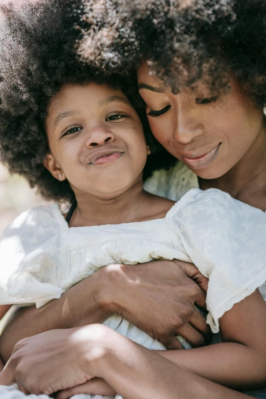 a woman holding a little girl in her arms, pexels, with afro, natural muted tones, slide show, 1 4 9 3