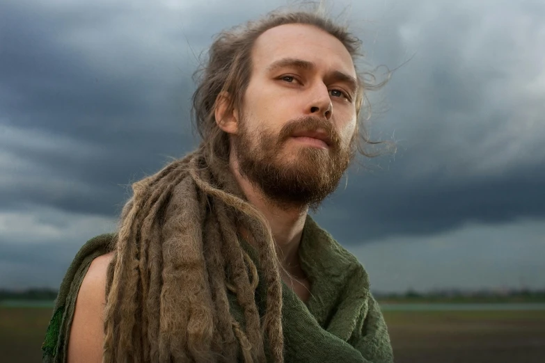 a man with dreads standing in front of a cloudy sky, a character portrait, inspired by Hallsteinn Sigurðsson, unsplash, renaissance, scruffy brown beard, wearing loincloth, ayahuasca, mid length portrait photograph