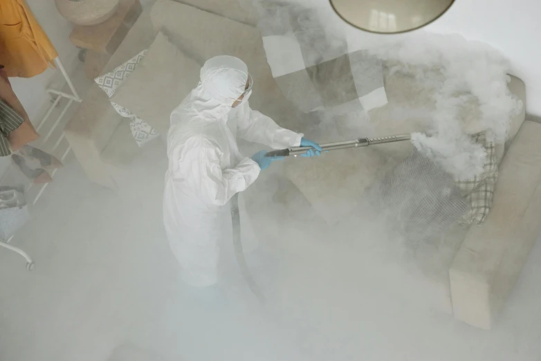 a person in a white coverall spraying something with a hose, pexels, a crystalline room, avatar image, a high angle shot, fume