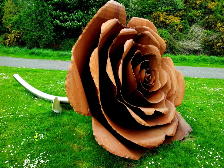 a large metal rose sitting on top of a lush green field, by Thomas Furlong, copper, made purely out of water, large rose flower head, made of cardboard