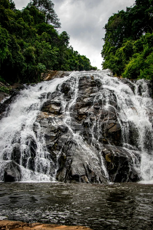 a large waterfall in the middle of a forest, malaysia jungle, taken with sony alpha 9, view up, splashes