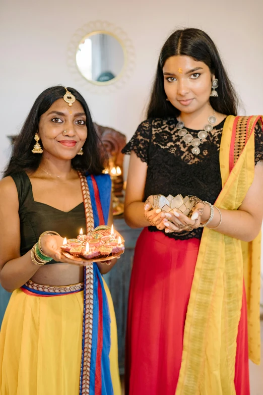 a couple of women standing next to each other, hindu ornaments, floating candles, curated collections, gen z
