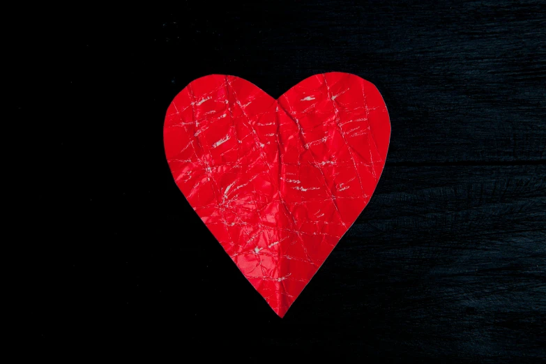 a red paper heart on a black background, an album cover, by Julia Pishtar, pexels, hurufiyya, cracked, avatar image, diverse, foil