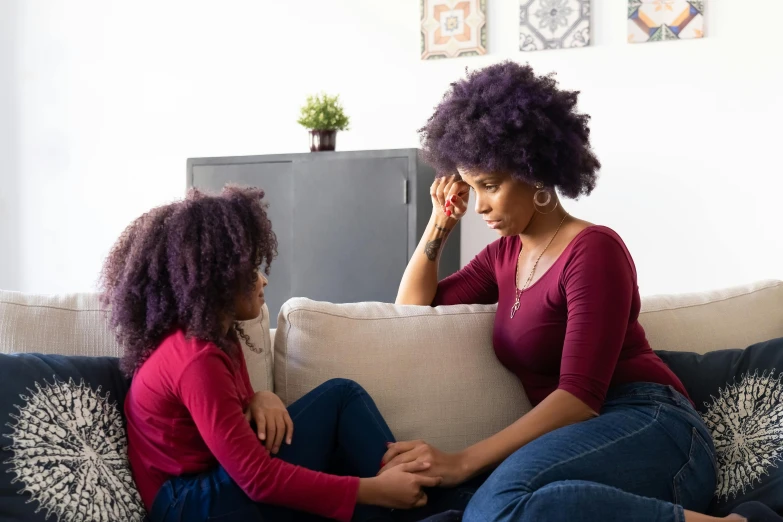 a woman and a little girl sitting on a couch, pexels, hurufiyya, red and purple coloring, heartbroken, african american young woman, professional image