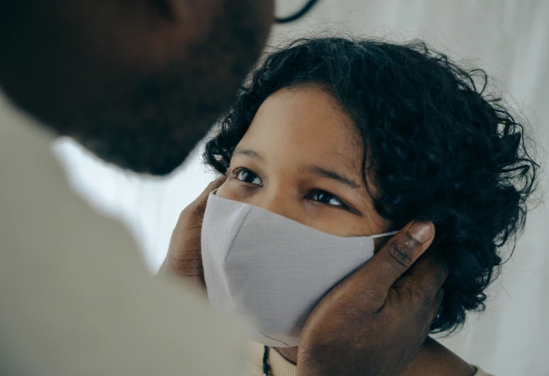 a man putting a mask on a woman's face, pexels contest winner, with a kid, gray canvas, caring fatherly wide forehead, ashteroth