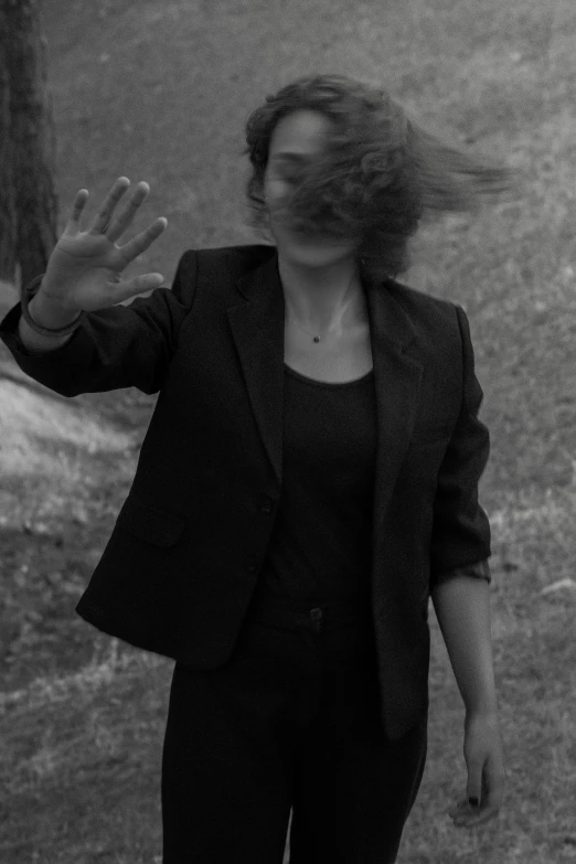 a woman with her hair blowing in the wind, a black and white photo, wearing black suit, séance, hands not visible, low quality photo