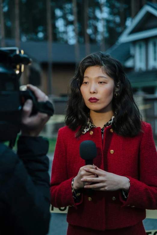 a woman in a red jacket holding a microphone, unsplash, private press, gemma chan, evening news program, still from film, journalism photo